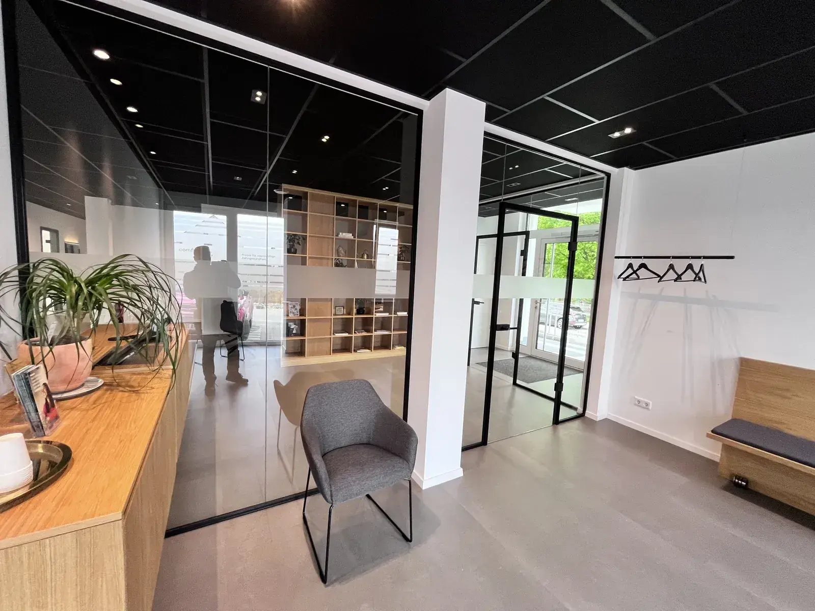 Empfang Confident Zahntechnik mit schwarzer Rasterdecke und Glas-Stahl-Trennwänden